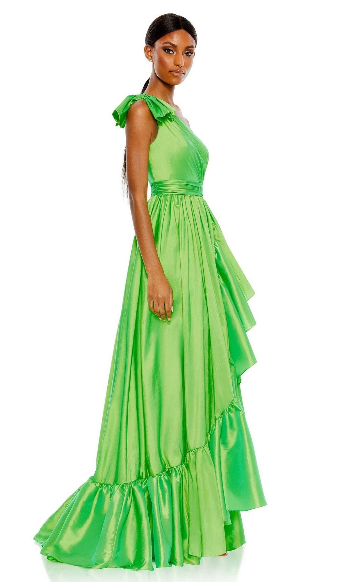 A woman models the Long Formal Dress 68027 by Mac Duggal, a bright green, one-shoulder gown with ruffle tiered details, as she stands slightly sideways against a plain white background.